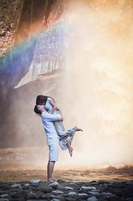 A couple hugging in front of a waterfall