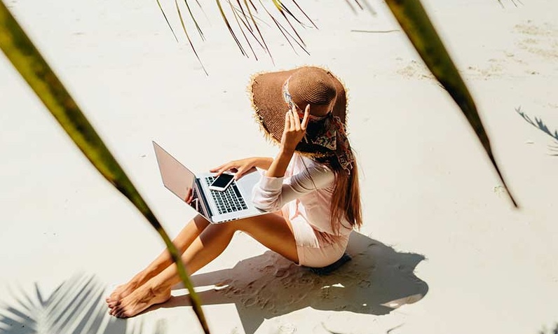 Girl on a beach with a laptop